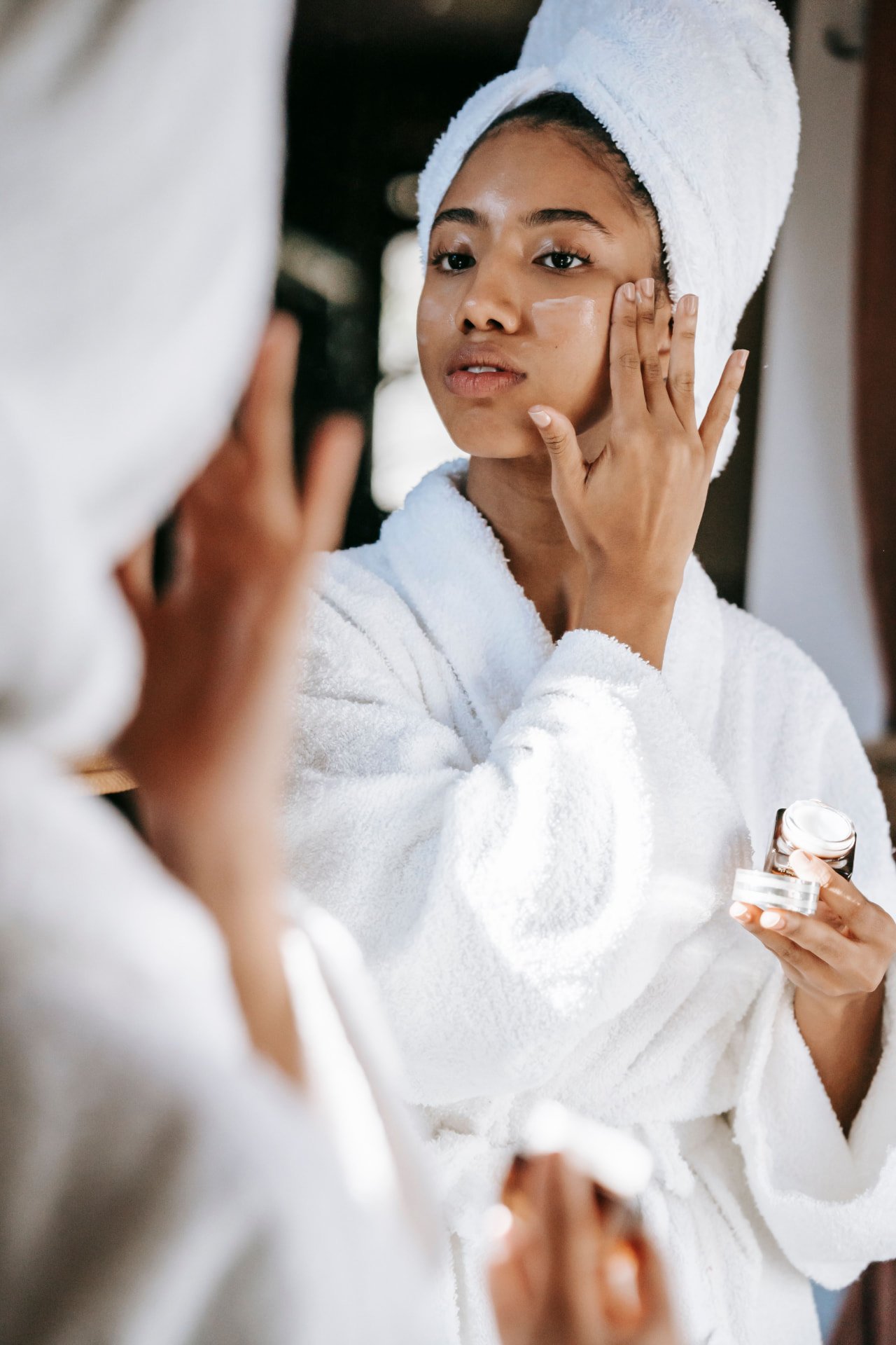 A woman gently examining her skin in a vanity mirror
